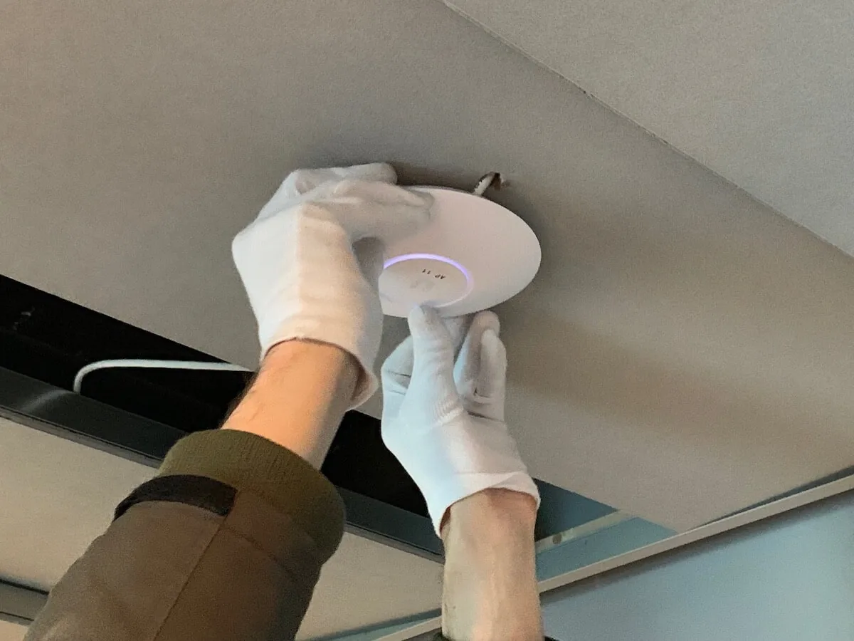 Monteur bevestigt een plat wifi-punt tegen een plafond in een woning